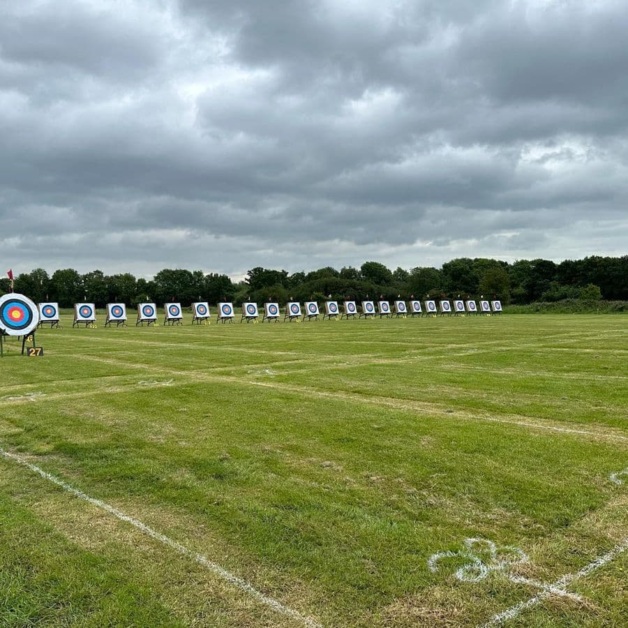 A long line of numbered target faces stretching across a field under a dramatic cloudy sky, no people visible.