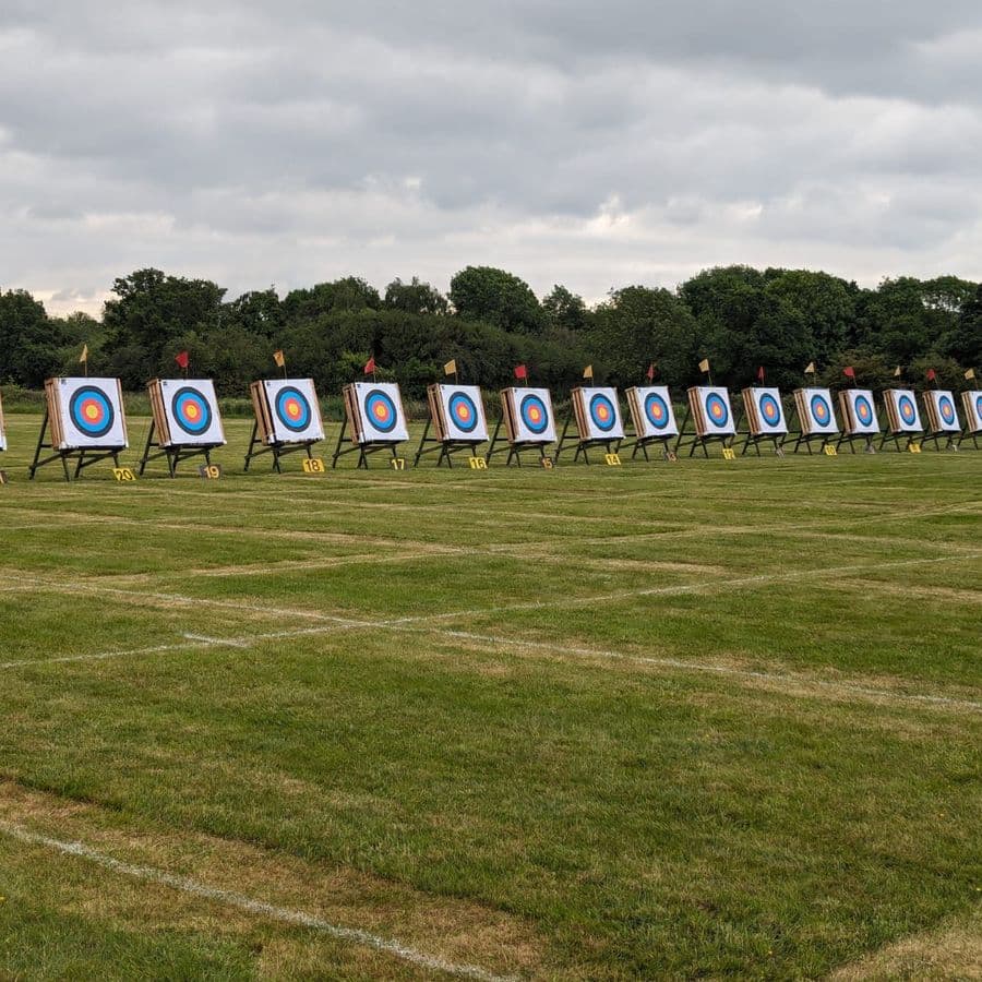 A long row of numbered archery targets set up across a grass field under a cloudy sky.